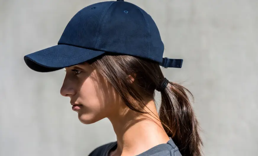 How to Wear a Hat with Long Hair Without Ruining Your Style 13 A woman wearing an adjustable navy baseball cap with long hair, showing how a loose strap prevents hair flattening and squashing.