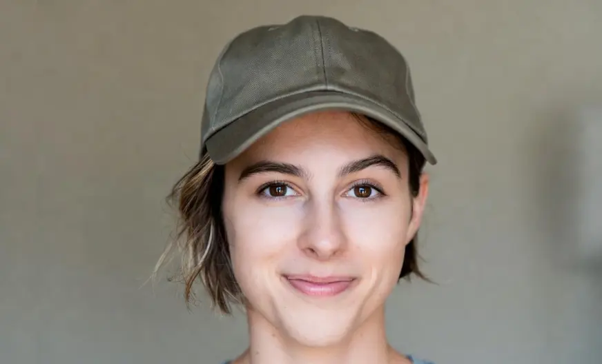 How to Wear a Hat with Short Hair and Look Amazing 6 A smiling woman wearing a baseball hat with short hair or pixie cut