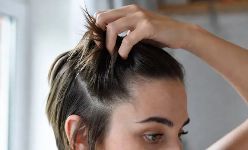 How to Wear a Hat with Short Hair and Look Amazing 3 A close-up shot of a woman styling her short hair with her fingers to add grip and texture.