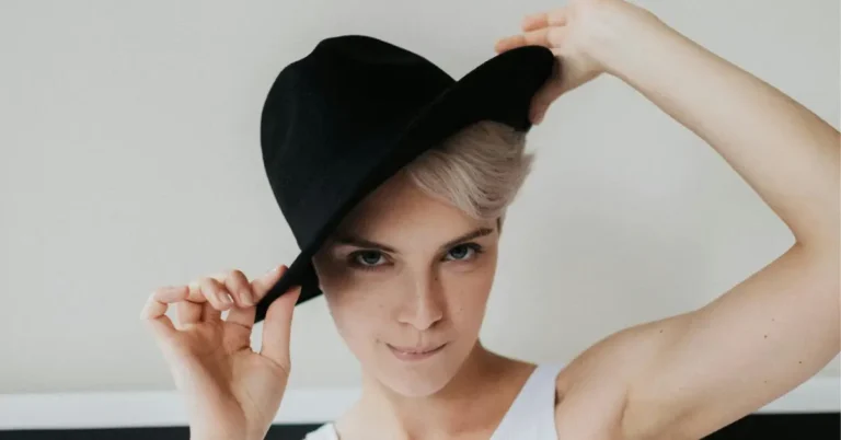 A woman with a pixie short haircut wearing a stylish black hat, showing how to wear hats with short hair