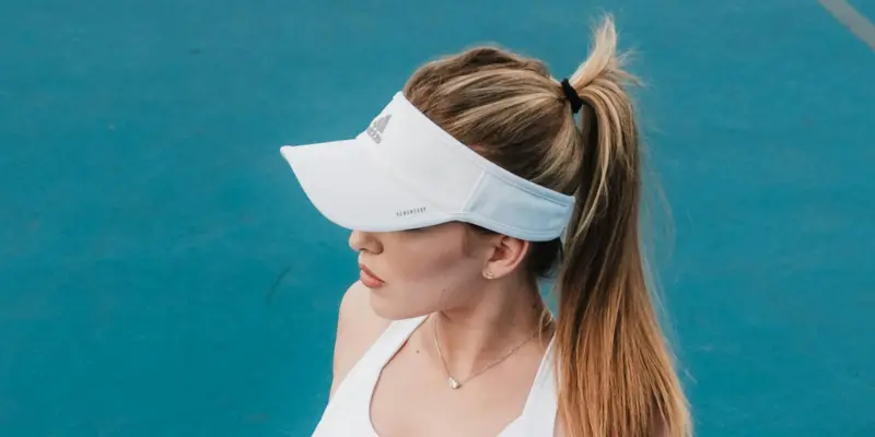 26 Different Types of Hats Explained (With Names, Styles & Pictures) 24 Woman wearing white visor cap at tennis court
