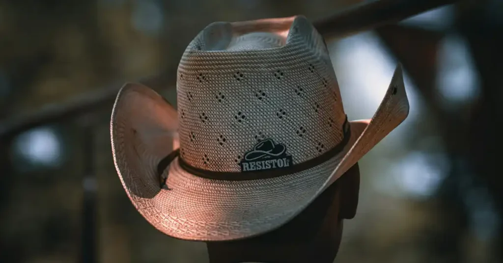 Handwoven straw cowboy hat with ventilation holes resting on a stone wall.