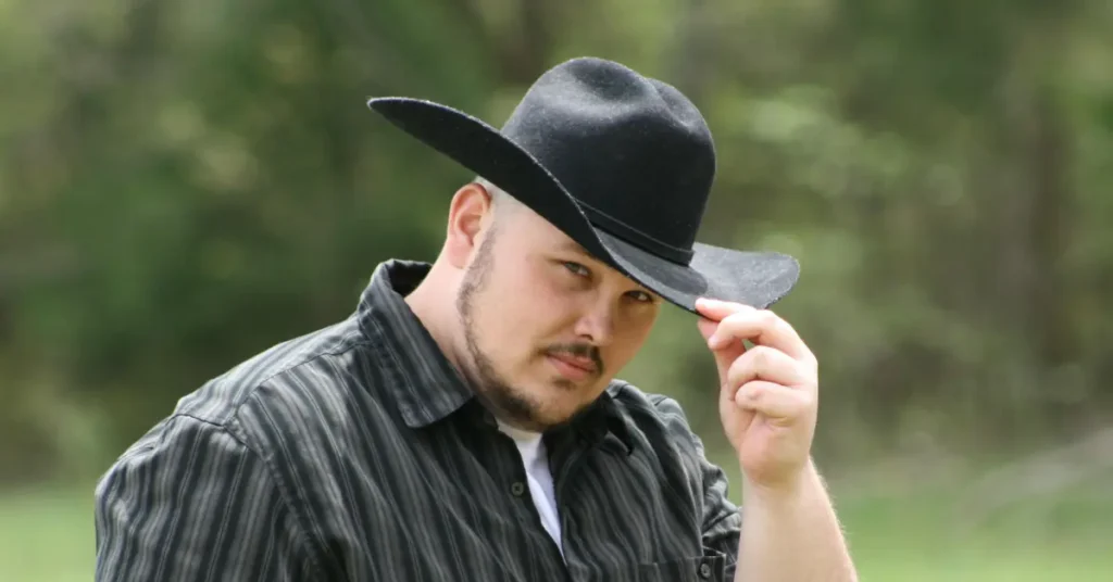 Man wearing a black cowboy hat tipping it forward as part of proper cowboy hat etiquette