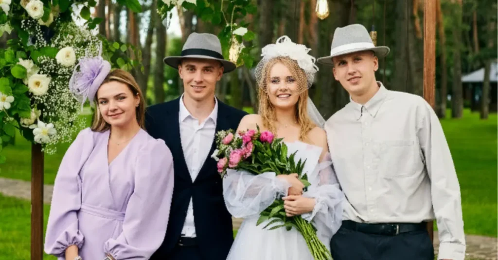 Group of wedding guests and bride wearing stylish hats, including fascinator and fedora, at an outdoor wedding ceremony.