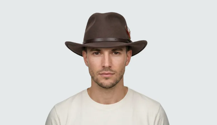 A man with a heart-shaped face wearing a brown felt outback hat with a feather.