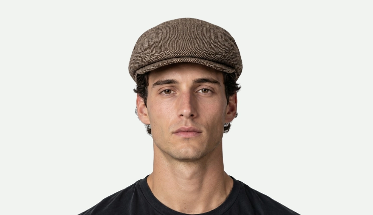 Man with oblong face wearing brown herringbone flat cap