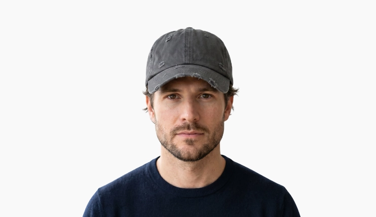 Man with square face wearing a baseball cap on a plain background
