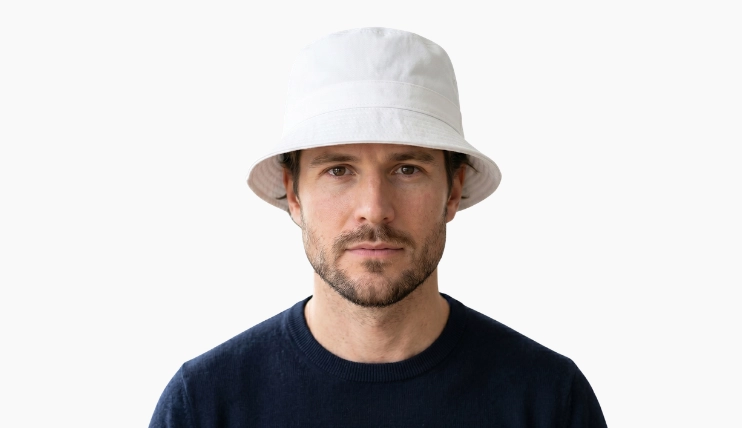 Man with square face wearing a white bucket hat on a plain background