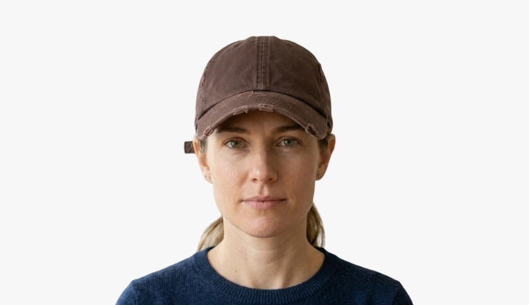 Woman with square face wearing a baseball cap on a plain background