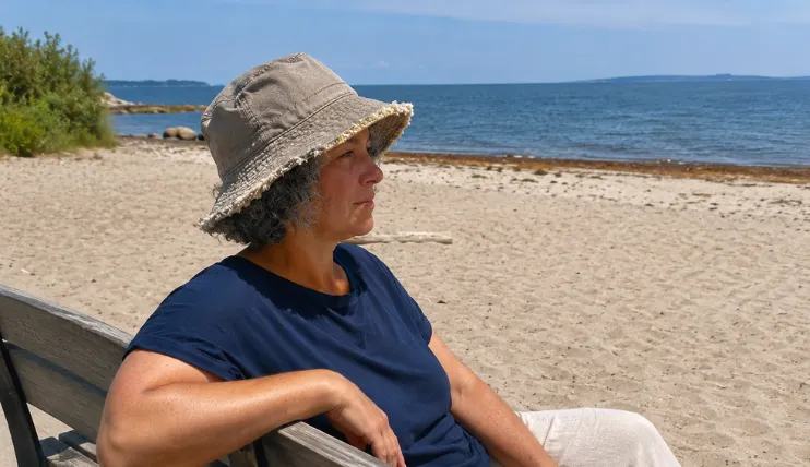 Woman with short curly hair wearing a frayed bucket hat at the beach