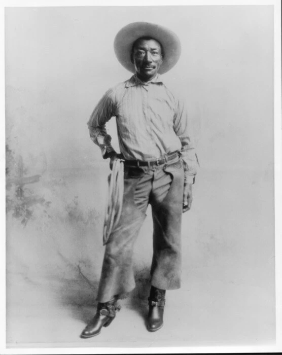Historical portrait of Bill Pickett, a famous Black cowboy and rodeo performer wearing a wide-brimmed hat and chaps.